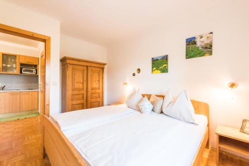 a bedroom with a white bed and a kitchen at Weingut Dietl in Riegersburg