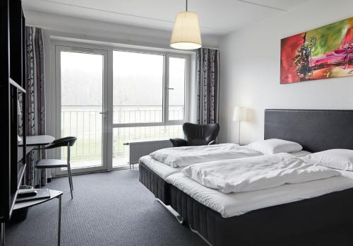 a bedroom with a bed and a chair and a window at Fjelsted Skov Hotel & Konference in Ejby