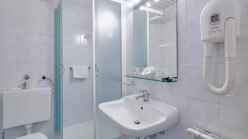 a white bathroom with a sink and a shower at Hotel Komodor in Dubrovnik