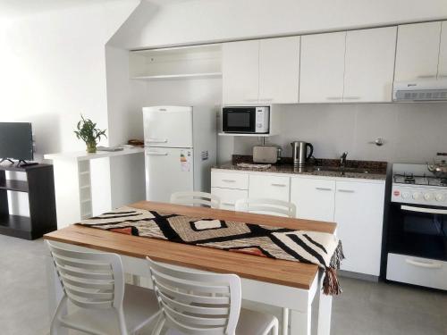 una cucina con mobili bianchi, tavolo e sedie di Complejo Las Rosas a Rafaela
