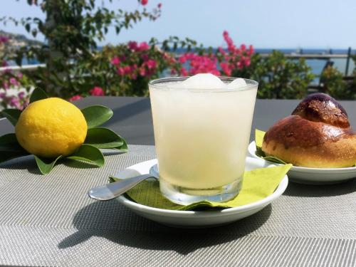 a drink on a plate with a lemon and a bagel at Hotel La Bussola in Milazzo