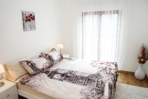 a white bedroom with a bed and a window at Apartman Aurora in Solde