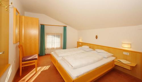 a bedroom with a large bed and a chair at Unterdornerhof in Lagundo