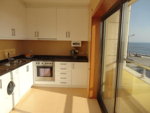 a kitchen with white cabinets and a view of the ocean at Beach front sunset apartment in Apúlia