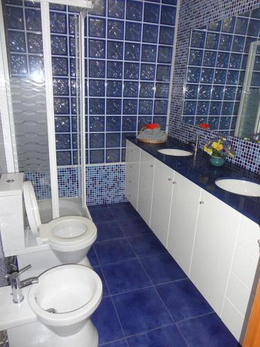 a blue tiled bathroom with a toilet and a sink at Beachfront sunset apartment in Apúlia