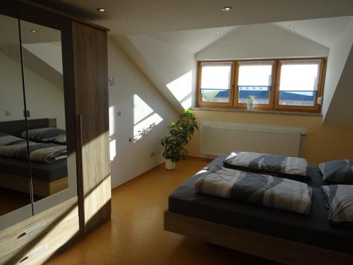 1 dormitorio en el ático con 2 camas y ventana en Ferienwohnung Hornauer, en Roding