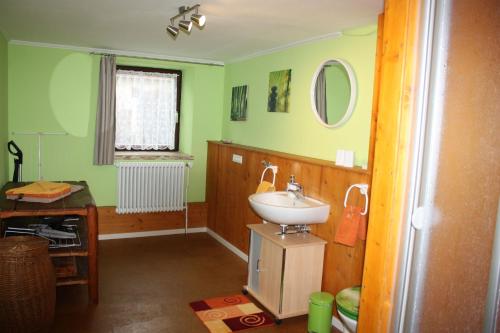 uma casa de banho verde com um lavatório e um espelho em Michlhof em Oberostendorf