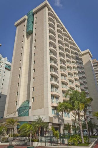 a large building with palm trees in front of it at Bourbon Residence Barra da Tijuca - Rio de Janeiro in Rio de Janeiro
