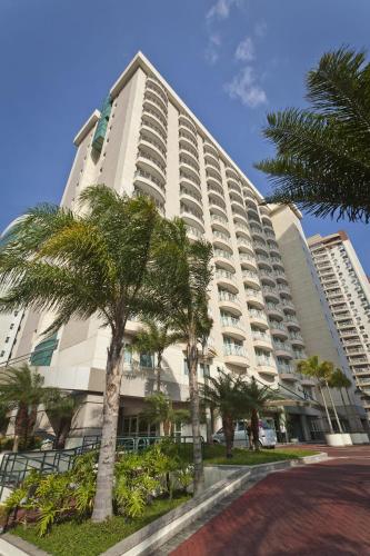 a large building with palm trees in front of it at Bourbon Residence Barra da Tijuca - Rio de Janeiro in Rio de Janeiro
