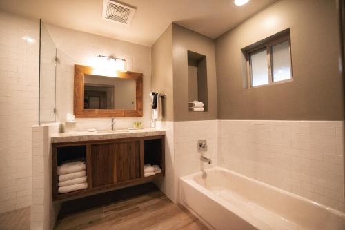 y baño con lavabo, bañera y espejo. en Driftwood Lodge, en Springdale