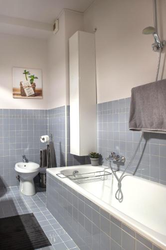 a blue tiled bathroom with a tub and a toilet at Vanessa Apartment in Como