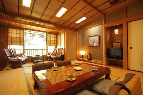 a living room with a table and chairs and a television at Morizuya in Toyooka
