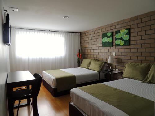 a hotel room with two beds and a window at Hotel Portal de Milán in Manizales