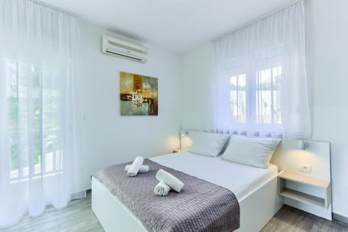 a white bedroom with a bed and a window at Stipe Residence in Podstrana