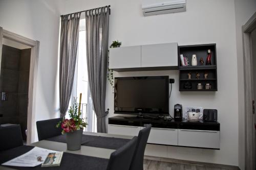 ein Wohnzimmer mit einem TV und einem Tisch mit Stühlen in der Unterkunft Palazzo Mormando - Modern Apartment in Neapel