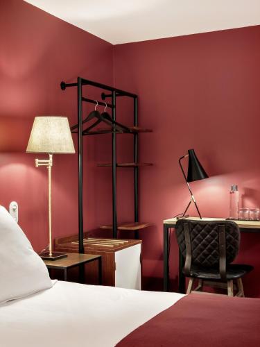 a bedroom with red walls and a bed and a desk at New Hotel Le Voltaire in Paris