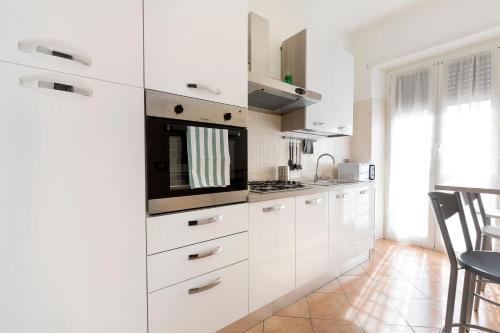a kitchen with white cabinets and a microwave at Enjoy Porta Furba in Rome