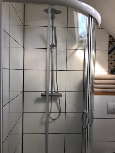 a shower in a bathroom with white tiles at Westfalische Apartments in Lennestadt
