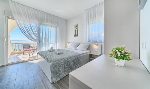 a white bedroom with a bed and a balcony at Stipe Residence in Podstrana