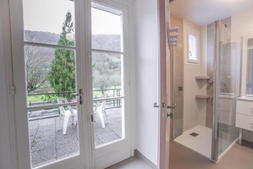 bagno con porta a vetri che conduce a un balcone. di Chez Bouchet a Licq-Athérey