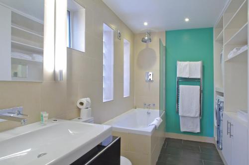 a white bathroom with a tub and a sink at Comfortable Waterloo Home Near Thames in London