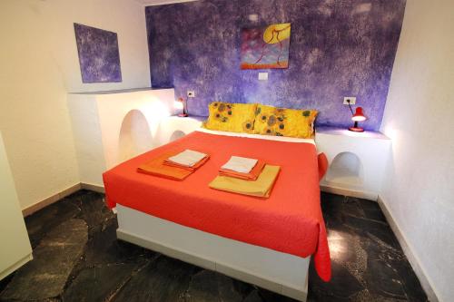 a bedroom with a bed with a red blanket and yellow pillows at Ierapetra La Luna Blu in Ferma
