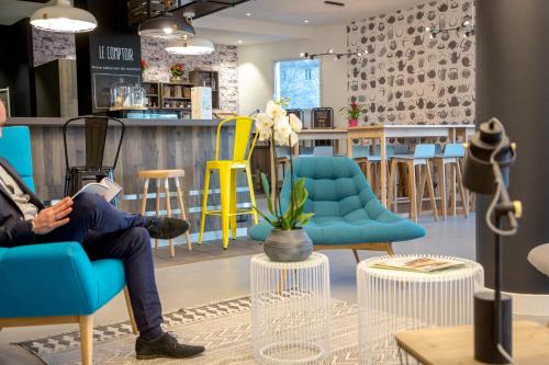 a person sitting in a blue chair in a store at ibis Lyon Sud Vienne Saint-Louis in Vienne