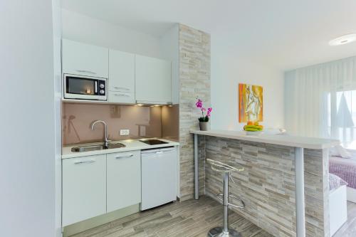 a white kitchen with a sink and a counter at Stipe Residence in Podstrana