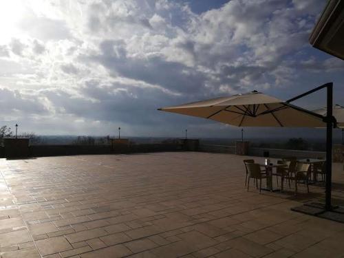 a patio with an umbrella and tables and chairs at Tenuta Terra e Sole in Castrocielo