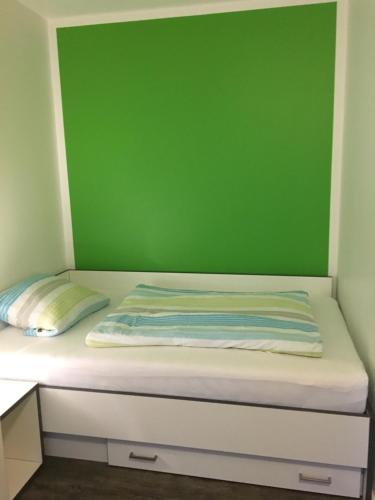 Bett in einem Zimmer mit grüner Wand in der Unterkunft Boardinghouse Paderborn in Paderborn