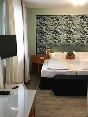 a hotel room with two beds and a tv at Flair Hotel zum Storchen in Bad Windsheim