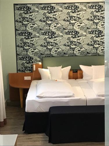 a bedroom with two white beds and a desk at Flair Hotel zum Storchen in Bad Windsheim
