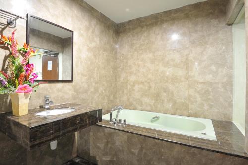 a bathroom with a tub and a sink and a mirror at Hallmark View Hotel in Melaka