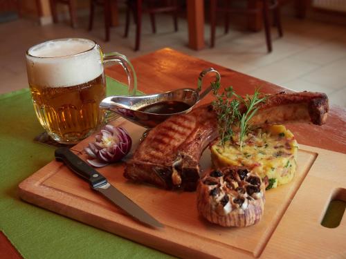 a cutting board with meat and a glass of beer at Penzion a Restaurace Simanda in Prague