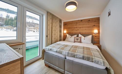 ein Schlafzimmer mit einem Bett und einem großen Fenster in der Unterkunft Saalbacher Perle Top 4 in Saalbach-Hinterglemm