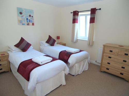 a bedroom with two beds and a dresser and a window at Allanfield Townhouse in Edinburgh
