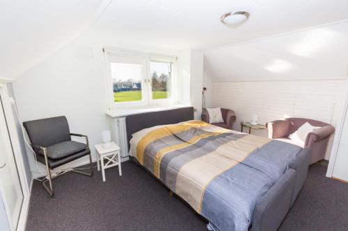 ein Schlafzimmer mit einem Bett, einem Stuhl und einem Fenster in der Unterkunft Bed & Breakfast Kroese in Oldenzaal