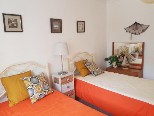um quarto com 2 camas com almofadas laranja em Apartamento Monte Gordo em Monte Gordo