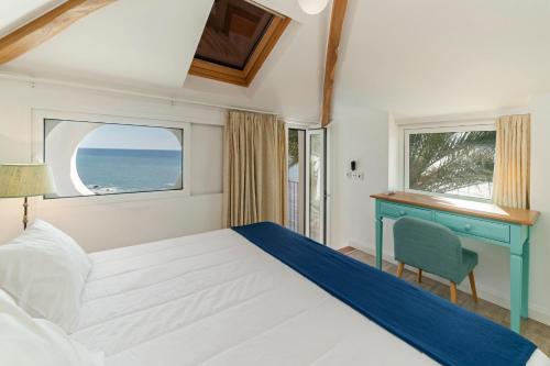a bedroom with a bed and a desk and a window at OurMadeira - Villa do Mar II, secluded in Arco da Calheta