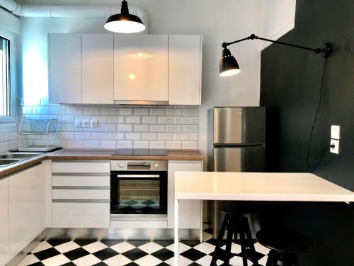 uma cozinha com armários brancos, uma mesa e um frigorífico em My Megaro Flat em Atenas