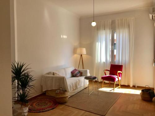 a living room with a white couch and a red chair at My Megaro Flat in Athens