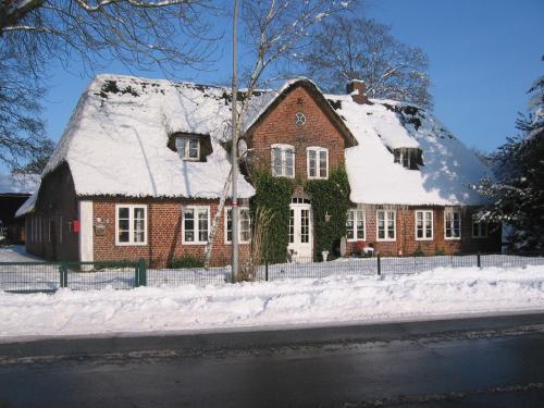 ein Backsteinhaus mit Schnee auf dem Dach in der Unterkunft Reiterhof Wollesen in Süderlügum