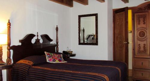 a bedroom with a bed with a mirror on the wall at Hotel Candelaria Antigua in Antigua Guatemala