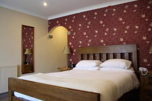 a bedroom with a large bed with a red wall at The Feathers in Pocklington