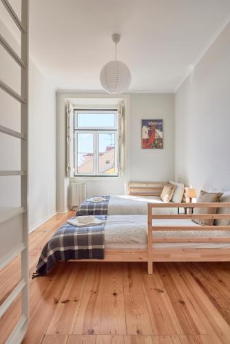 a white bedroom with a bed and a window at Rua dos Remédios 179 in Lisbon