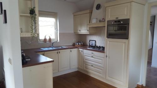 a kitchen with white cabinets and a sink at Vakantiehuis de wilgenhof in Wetering