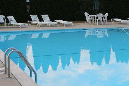 a blue swimming pool with chairs and a table at Tides Inn at Stehli Beach in Locust Valley