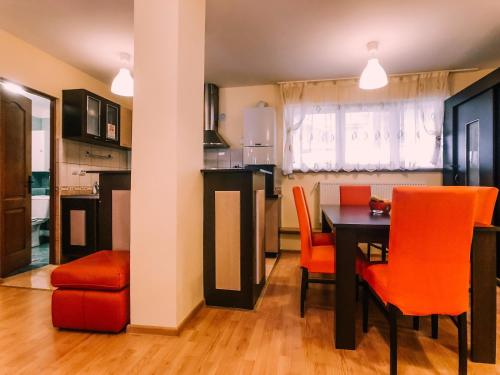 a kitchen and dining room with a table and orange chairs at Spacious Apartment near Peles in Sinaia