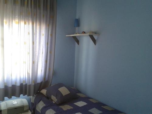 a small bedroom with a bed and a window at Precioso piso al lado de la playa in Cádiz