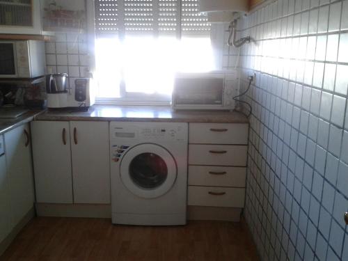 a kitchen with a washing machine and a window at Precioso piso al lado de la playa in Cádiz